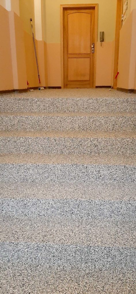 Kamenný koberec na schodech bytového domu.